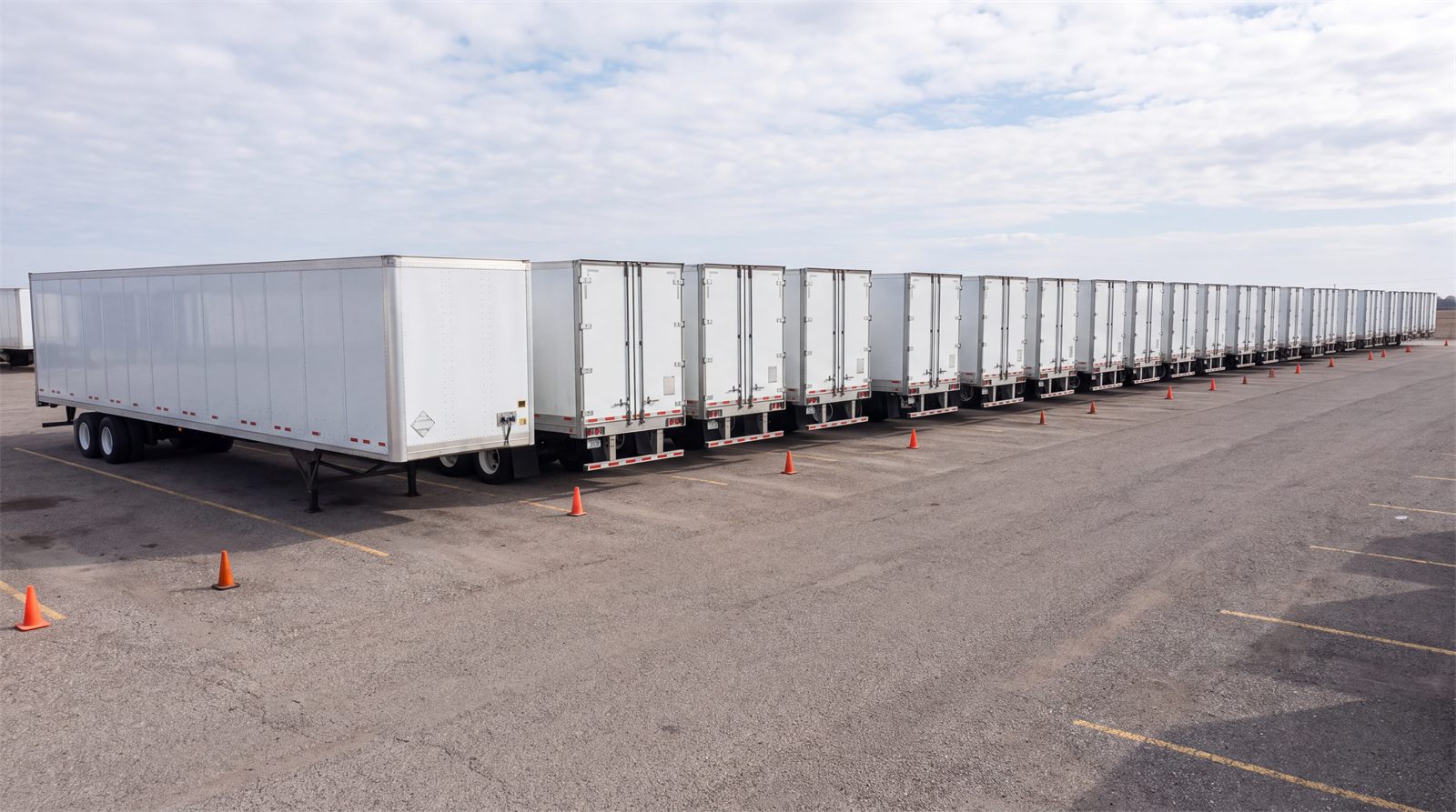 Row of empty dry van trailers staged in a drop lot