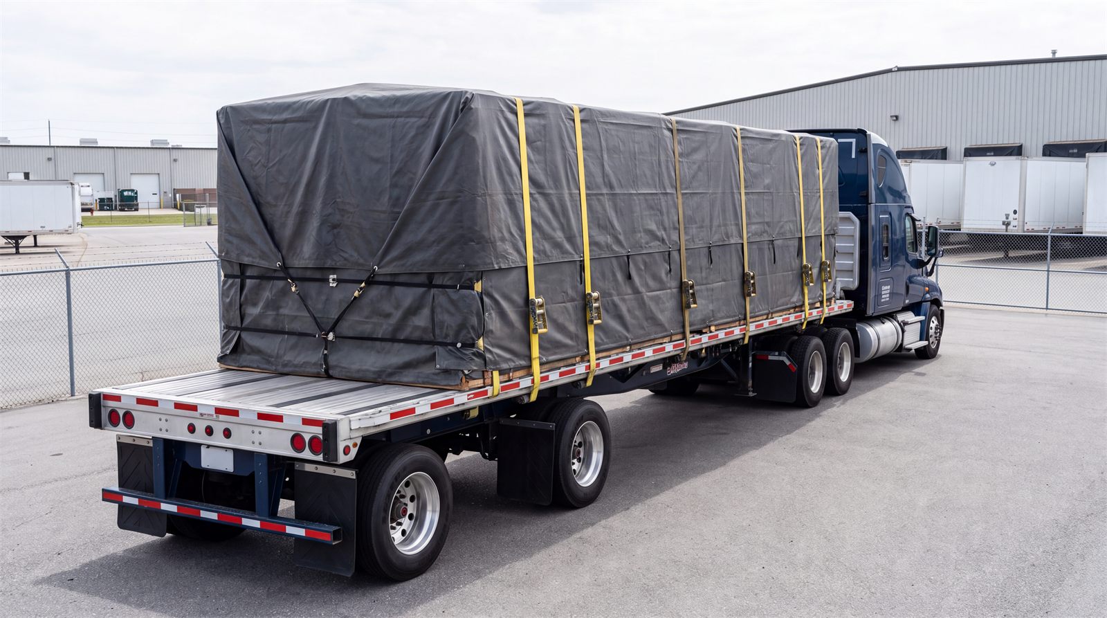 Tarped and strapped flatbed load parked at a distribution yard
